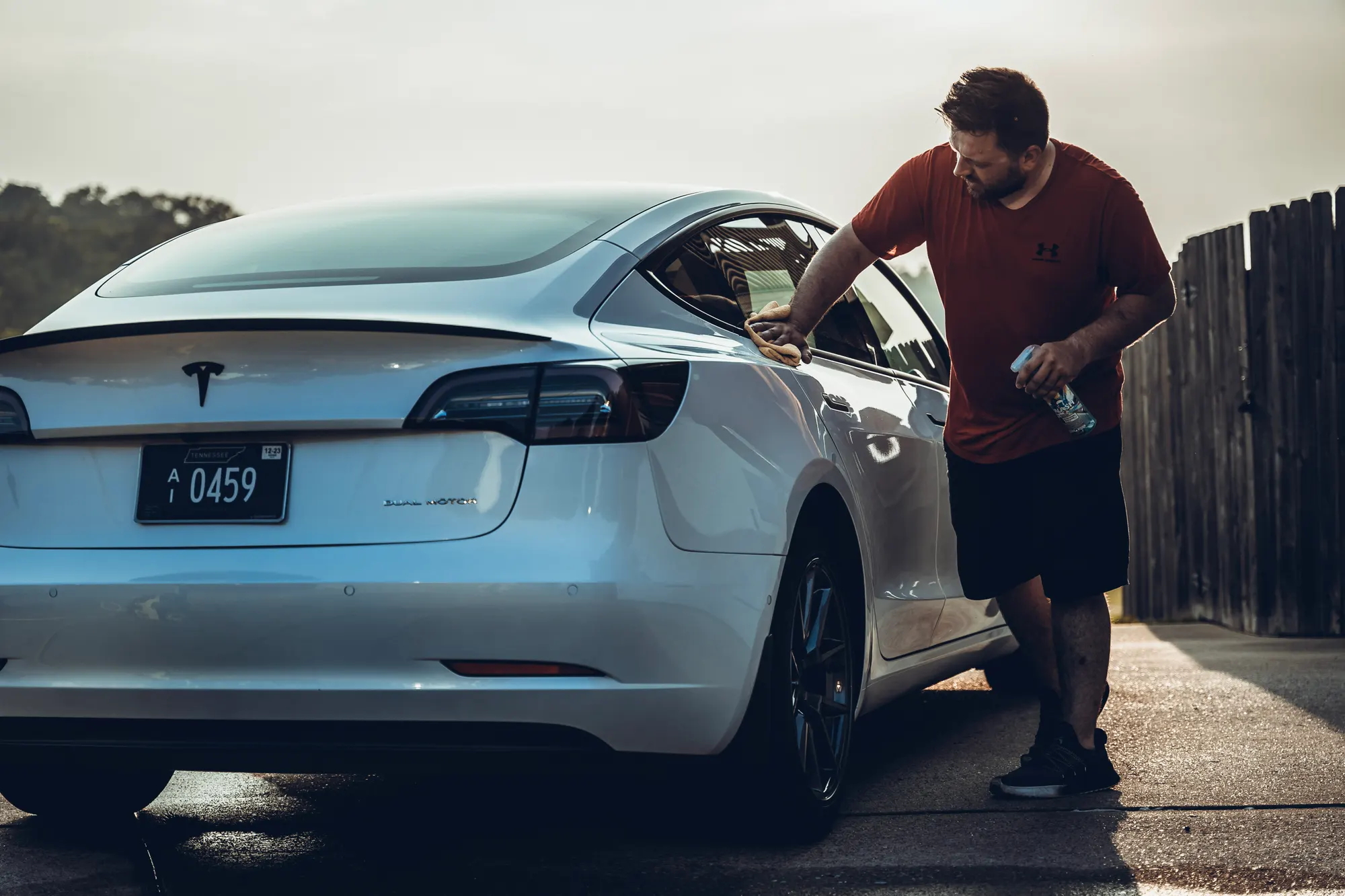 Detailer polishing a white Tesla at golden hour